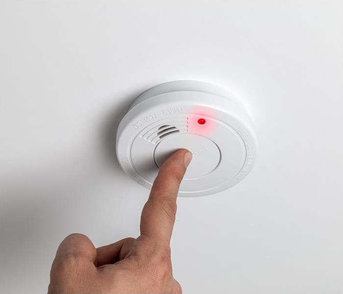 white fire alarm being tested by a person