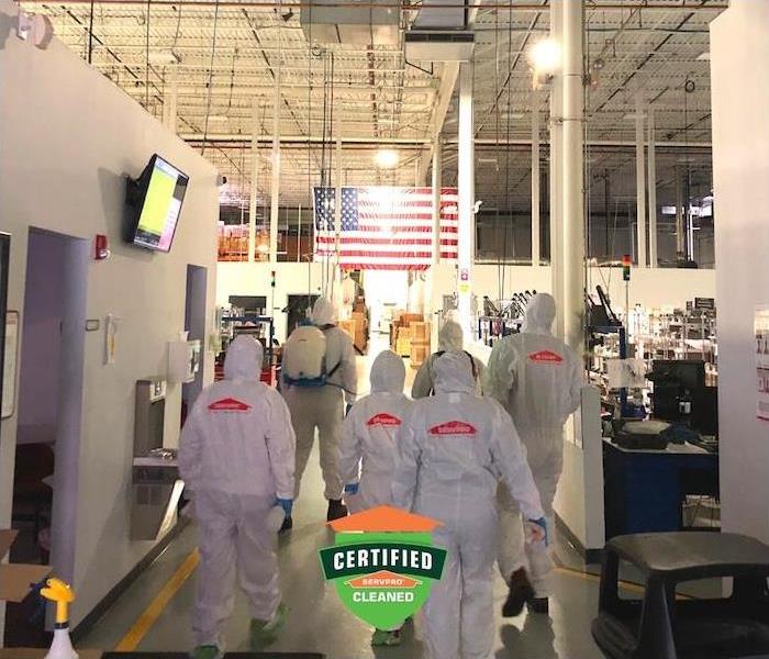 a crew of SERVPRO employees in PPE gear walking inside commercial building