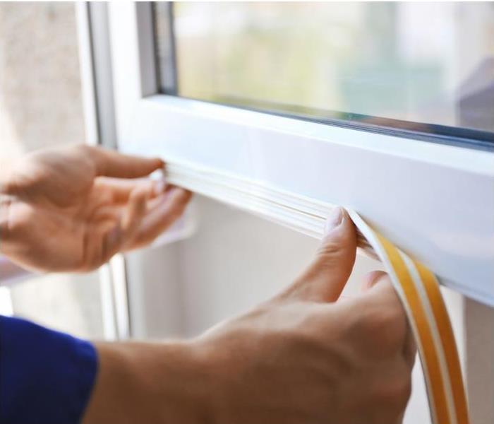 a person placing weatherstripping on a white window