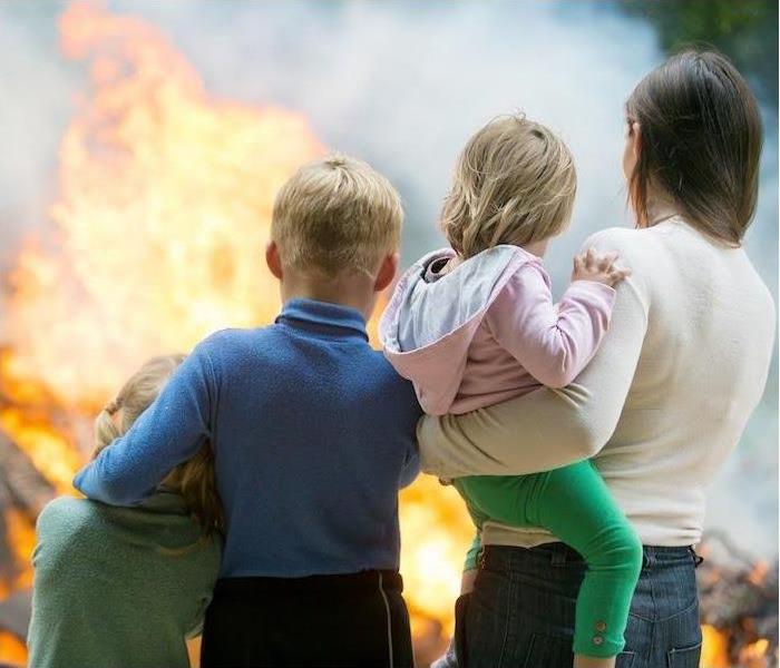 a girl, boy and women holding toddler looking at fire