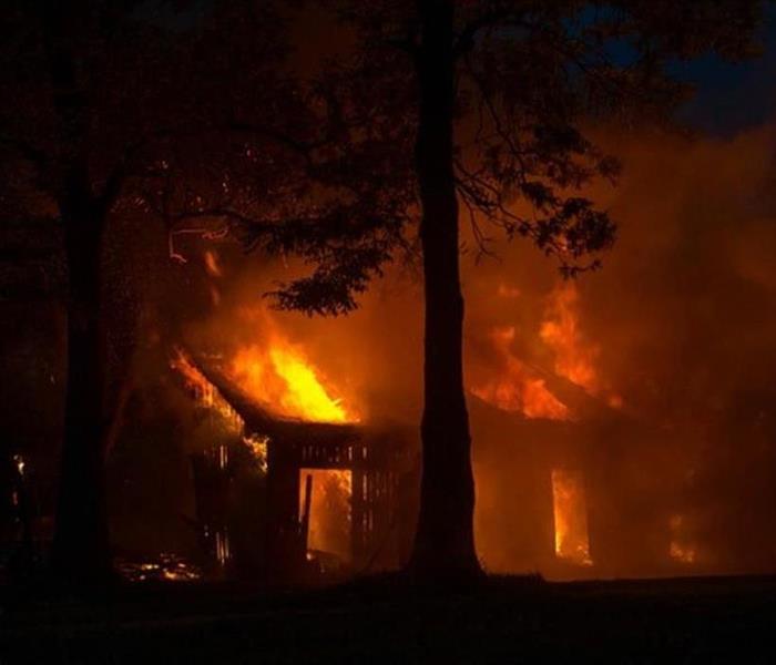 a house engulfed in flames at night
